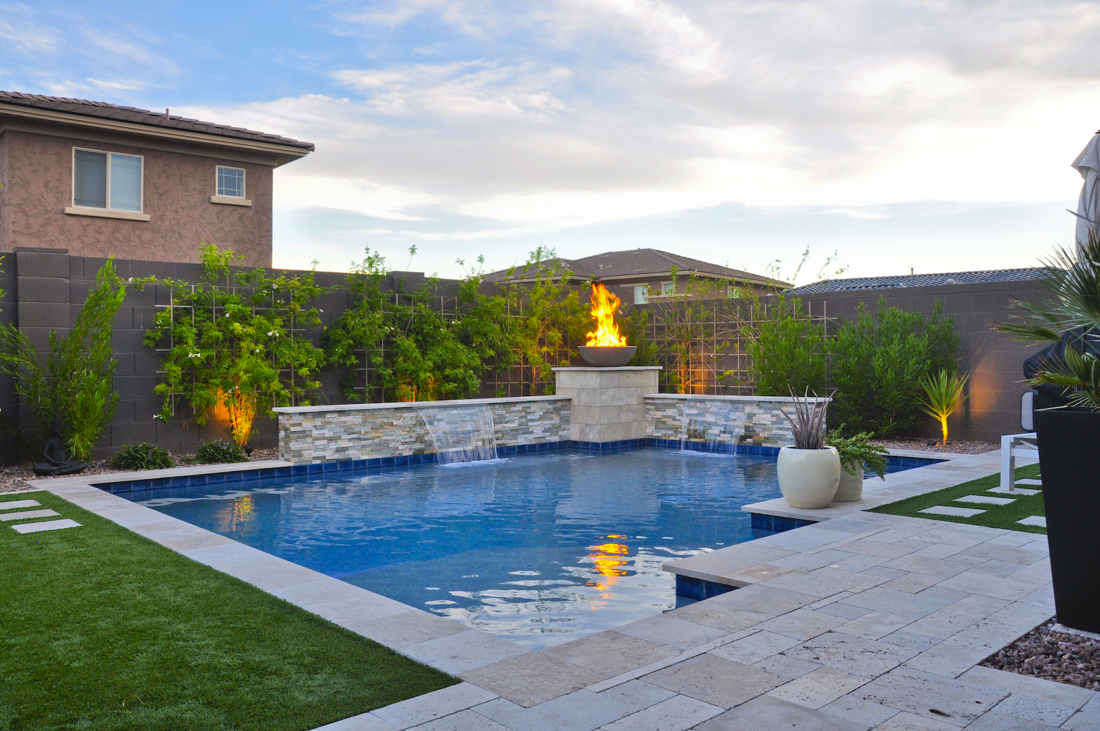 A swimming pool and an outdoor fireplace in a Zen-style garden